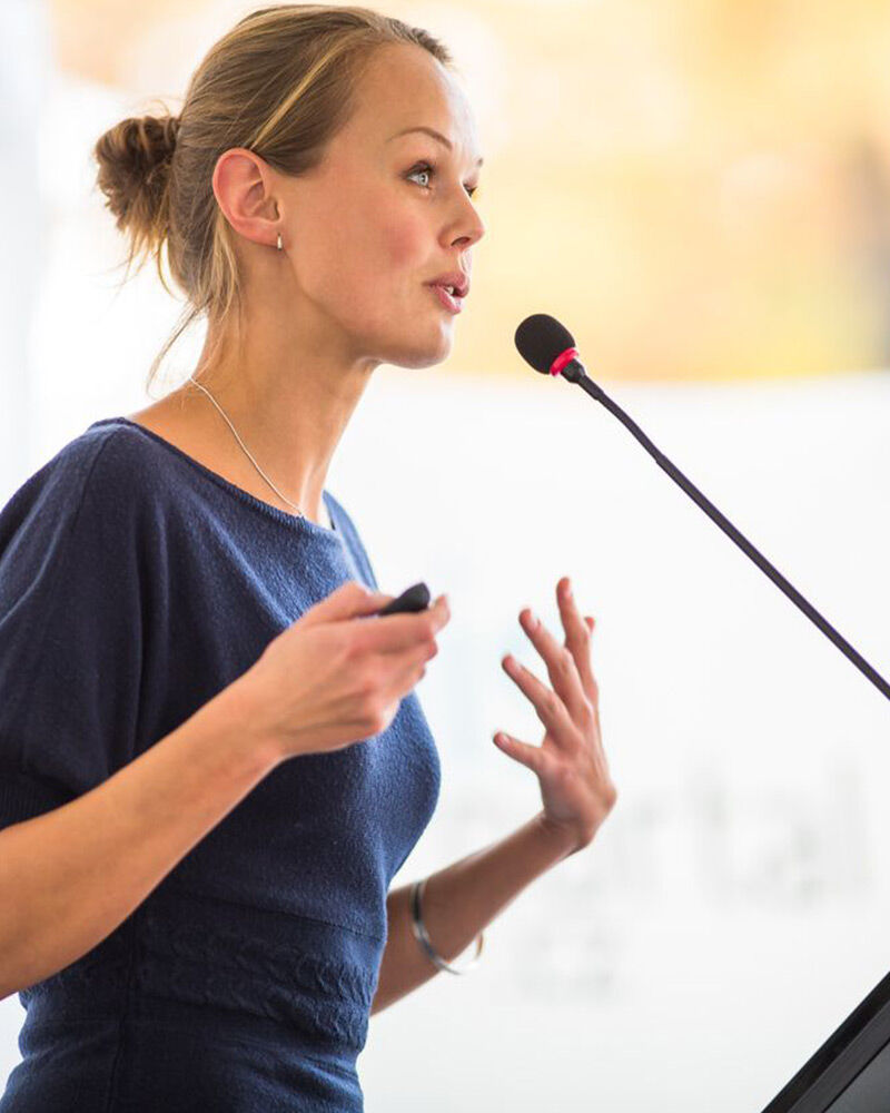 A woman speaking passionately into a microphone during a presentation.